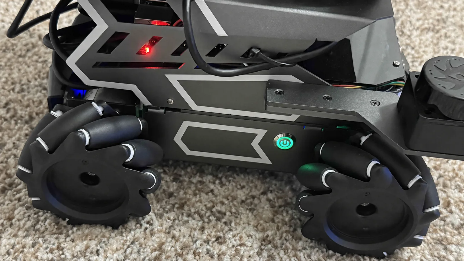 Close view of the ROSMASTER M3 Pro front power button, chassis, and wheels